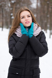 Fototapeta Koty - beautiful young woman in gloves and a scarf in a winter park