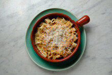 Top shot of guanciale and four cheese truffle mac in a red mug on a green plate