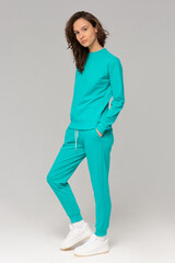 Smiling woman with thick curly hair in a mint suit of hoodies and sweatpants. Mock-up.
