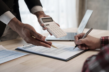 Wall Mural - Holding calculator, showing house cost and interest, Credit approver, businessman in male suit and house toy model mockup Home loan mortgage approval concept. After signing the contract