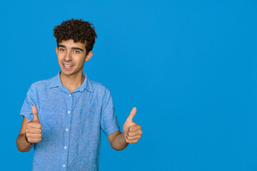 young boy in casual clothes is showing Ok sing with two hands, looking at camera and smiling, against cyan isolated background, close-up