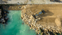 Aerial View Of Waterfront Construction Site With Excavator. Bulldozer Working On A Breakwater Construction