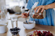 Close-up of young woman preparing muesli for breakfast in her kitchen, morning routine and healthy lifestyle concept.