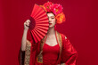 © Nattakorn - Young asian woman wearing qipao cheongsam dress with Chinese folding fan on red background for Chinese new year festival