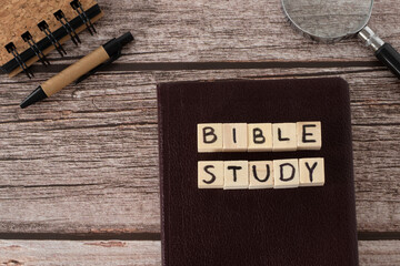 Wall Mural - Bible study text written on wooden cubes, Christian holy book, notebook, magnifying glass, and pen on wooden background. Top table view. Searching and exploring Scriptures concept.