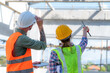 © EKKAPON - Structural engineer and foreman worker with blueprints discuss, plan inspecting for the outdoors building construction site.