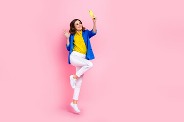 Wall Mural - Full size photo of cheerful excited girl jumping hold telephone take selfie arm waving isolated on pink color background