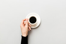Minimalistic Style Woman Hand Holding A Cup Of Coffee On Colored Background. Flat Lay, Top View Espresso Cup. Empty Place For Text, Copy Space. Coffee Addiction. Top View, Flat Lay