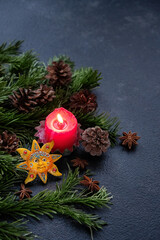 Wall Mural - Red candle, sun amulet, cones, fir branches on dark abstract background. Witchcraft, spiritual Esoteric Ritual. wiccan altar. symbol of Yule, Winter Solstice holiday