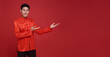 Happy Chinese new year. Asian man presenting or showing open hand palm with copy space introduce for product isolated on red background.