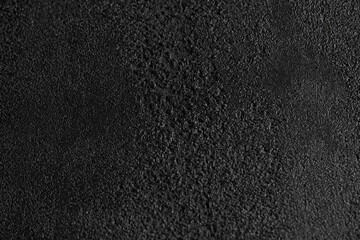 Close up of dark grey, grainy surface for modern, unusual background design. Rough texture of black covering backdrop. Concept of textures and background.