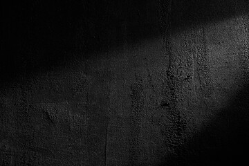 Black wall rough texture background, concrete floor or old grunge backdrop, illuminated by sun ray. Close up of dark graphite surface for modern background design. Concept of textures and background.