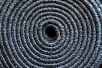 Relief texture of rolled up grey carpet as background. Close up of coiled natural dark rope, jute spiral circle pattern from above. Concept of textures and backgrounds. 