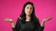 © Robert Peak - Portrait of happy pretty woman 20s shrugging shoulders and gesturing I do not know isolated on pink background.