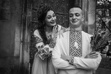 Canvas Print - Black and white photo, young, emotional, happy couple in love, family, hugging, in Ukrainian embroidered shirts against the background of the old city. Young people hug in the old town of Lviv 