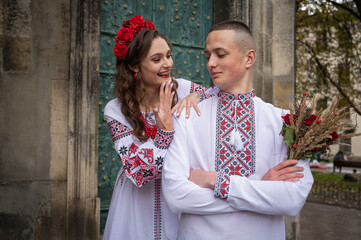 Wall Mural - Portrait of a happy young couple in love, a family walking in the old city of Lviv in traditional Ukrainian shirts, walking holding hands. Young people hug in the old town of Lviv