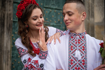 Wall Mural - A young, emotional, happy couple in love, a family walks through the old city of Lviv in Ukrainian embroidered shirts, holding hands against the background of the old city. Young people hug in the old