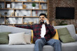 © sofiko14 - Handsome bearded positive man sitting on couch and calling to his friend using smartphone indoors. Smiling male freelancer taking break during working process at home.