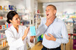 © JackF - Man complains to a female pharmacist about a sore throat. Help in choosing a medicine in a pharmacy