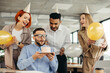 © dsheremeta - Happy businessman blowing out a candle on cake while celebrating Birthday with female coworkers in the office.