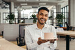 © dsheremeta - Happy Hindu businessman holding cake with lightened candle in the office and looking at camera.