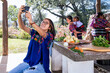 © Mario Guerra - Chica haciendose una selfie con el telefono celular a ella su abuela y su mama. Familia cocinando al aire libre.