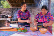 Retrato de madre enseñando a su hija a cocinar con una piedra de moler y una vajilla de arcilla. Mujeres hispanas. 