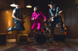 © PoppyPix - Rock band jumping. Two guitarists and one vocalist jumping high in the air inside their garage studio. Indoor full length shot. High quality photo