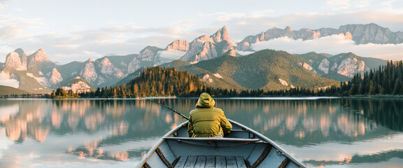 rear view, of a young man, riding in a boat fishing by the lake at sunset