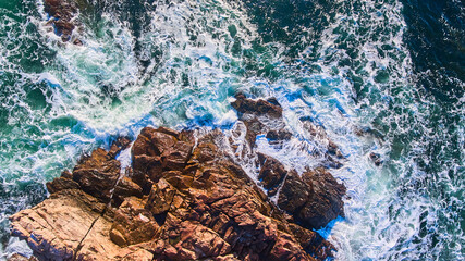 Wall Mural - Waves crashing into rocky coasts of Maine aerial from above looking down