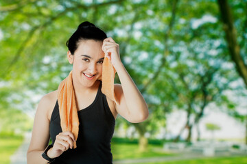 Wall Mural - Smiling woman wiping sweat after workout at park