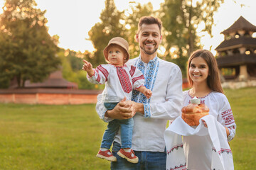 Sticker - Happy cute family in embroidered Ukrainian shirts with korovai bread on sunny day. Space for text