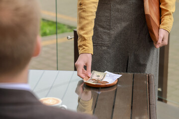 Sticker - Waitress taking tips from wooden table in outdoor cafe, closeup