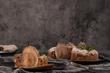 Delicious spice cake with pear, ginger and cinnamon on a dark kitchen counter.