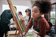 © tigercat_lpg - African American girl concentrates on acrylic color picture painting on canvas with students group in art classroom, creative learning with talents and skills in elementary school studio education.