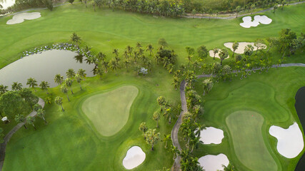 Aerial view of green golf course and putting green, Aerial view of green grass and coconut palm trees on gree golf field, fairway, sand bunker  and putting green.