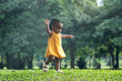 Cute little child baby girl playing in sunny summer park, little African Asian girl with braided hair walking at green lawn park, enjoying outdoor recreation
