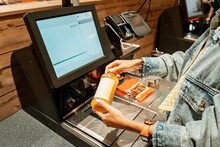A girl customer scanns and pays for bottle of juice from a supermarket in an automated self-service checkout terminal