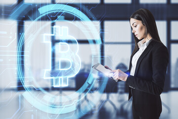 Canvas Print - Attractive young european businesswoman using tablet with glowing bitcoin icon on blurry office interior background. Cryptography, money and investment concept. Double exposure.