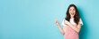 Portrait of happy smiling female model with glamour blush, pointing fingers left and looking at promo offer, showing an advertisement copy space, blue background