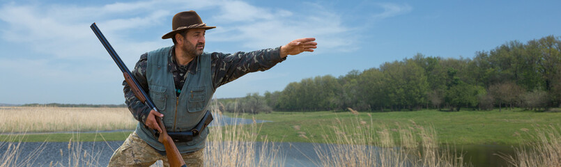 Wall Mural - Hunter man in camouflage with a gun during the hunt in search of wild birds or game.