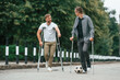 © standret - Two men with crutches is outdoors on the road. With a soccer ball