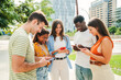 © Jose Calsina - Multiracial group of young smiling students enjoying and having fun with their cellphones. Teenage friends sending text messages to each other on after class around campus. High quality photo