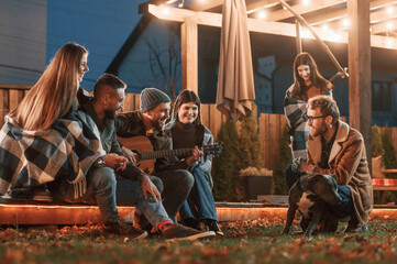 Wall Mural - Cute dog. Group of people is spending time together on the backyard at evening time