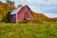 Red Barn In Country Fields Surrounded By Mountains Of Peak Fall Foliage Trees