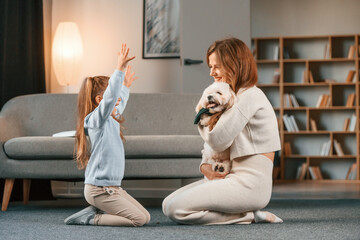 Woman is giving pet for the girl. Present for the daughter. Mother is at home with maltese dog