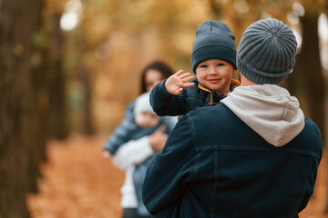 Wall Mural - Boy is on the dad's hands. Father with his son on hands walking with mother that is with toddler