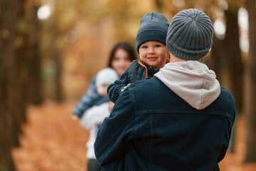 Wall Mural - Boy is on the dad's hands. Father with his son on hands walking with mother that is with toddler