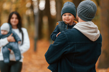 Boy is on the dad's hands. Father with his son on hands walking with mother that is with toddler