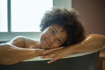 Portrait of smiling woman leaning on edge of bathtub